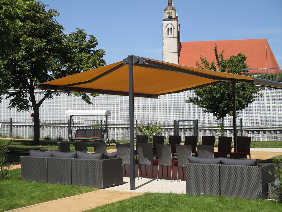 Freistehende Kragarm-Markise in einer Parkanlage mit Lounge-Sitzgruppe