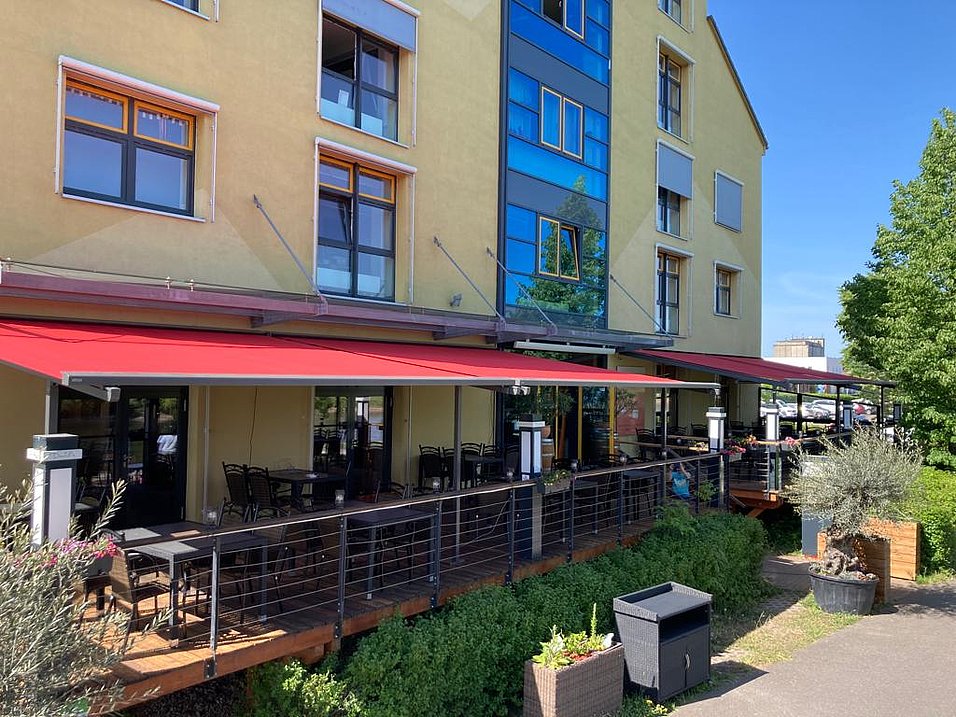 Rote Gelenkarmmarkisen über einer Restaurantterrasse